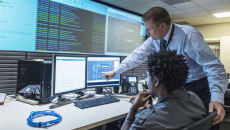 Two workers looking at multiple computers