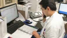 Doctor on telephone in front of book and screens