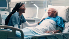 Woman talking to a patient in a hospital bed.