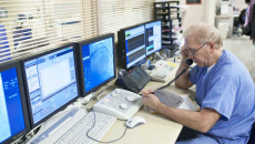 Doctor on phone in front of multiple computer screens