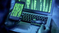 Person on smartphone has credit card out and is also looking at a laptop screen