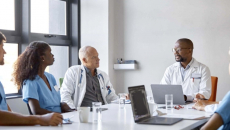 Clinicians talking at a boardroom table