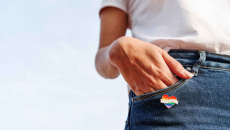 A rainbow heart pin worn on a jeans pocket
