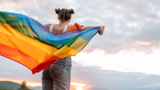 Person holding LGBTQ+ rainbow flag