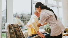 Person assisted from a chair by healthcare worker