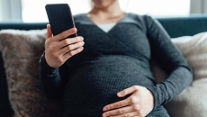 Pregnant person with cellphone. Photo: Oscar Wong/Getty Images