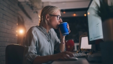 Person at desk sipping from a coffee cup