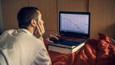 Person on computer looks at a declining stock's chart
