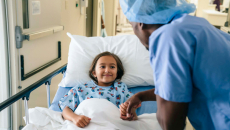 Healthcare worker visits child in hospital bed