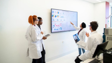 Medical professionals with a large screen of graphs and pie charts