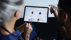 Two people examine information on a tablet