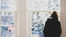 Silhouette of person looking out a window