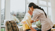 Nurse helping senior into a chair