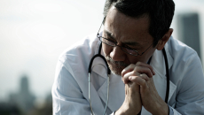Medical professional seated, appearing dejected