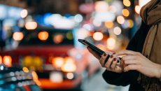 Street scene of person with phone and cars at night