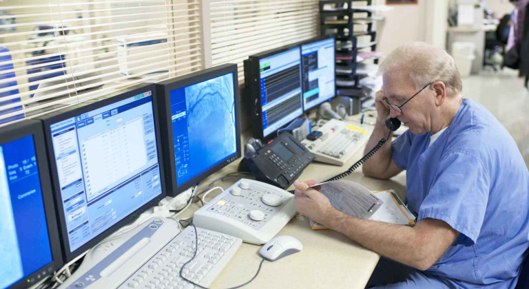 Doctor on phone in front of computers