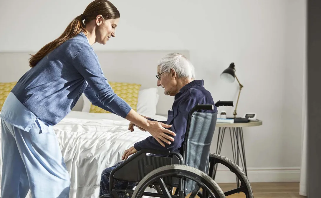 Home health worker helping a man in a wheelchair Home health worker helping a man in a wheelchair