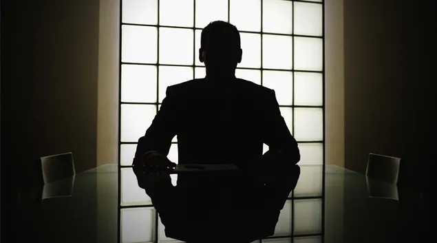 Silhouette of business executive looking out boardroom window