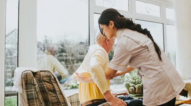 Nurse helping senior into a chair Nurse helping senior into a chair
