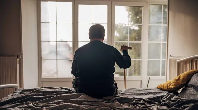 Silhouette of senior staring out nursing home window