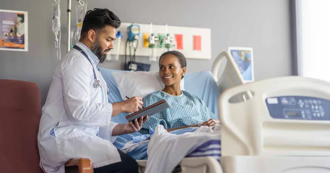 Doctor talking to patient and taking notes with a tablet in a hospital room