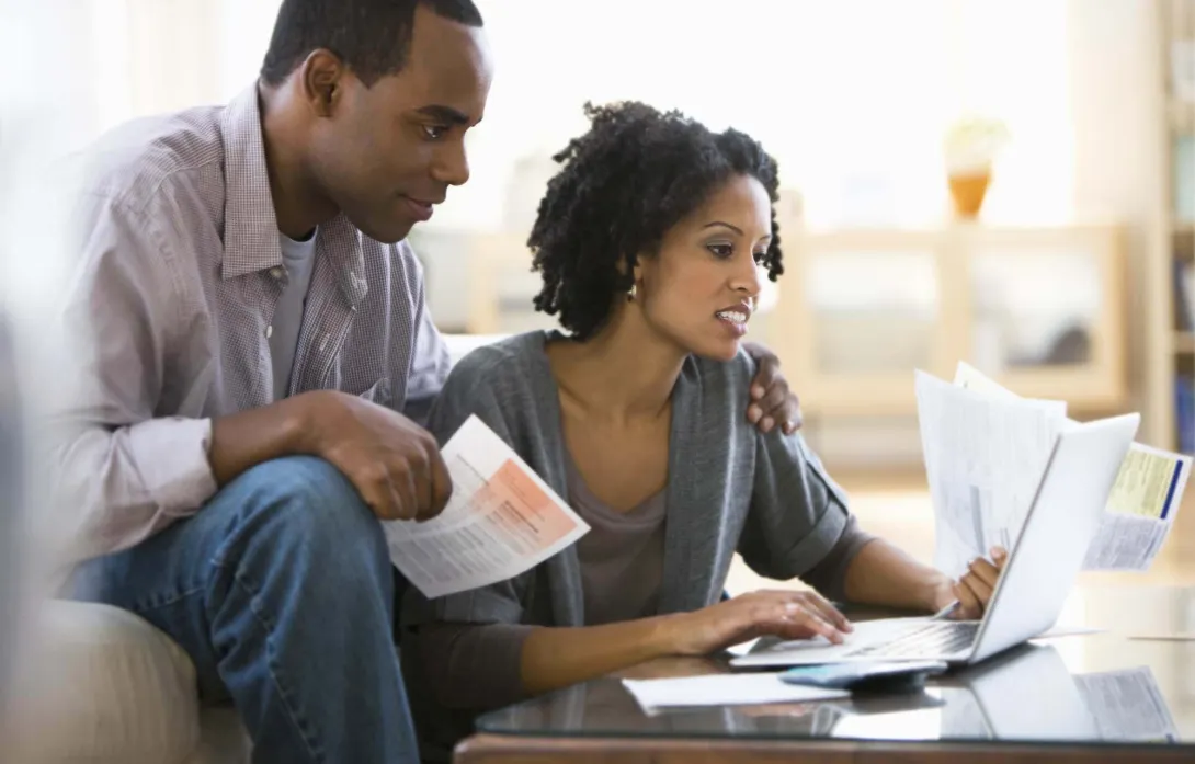 Couple figuring out bills in front of a computer
