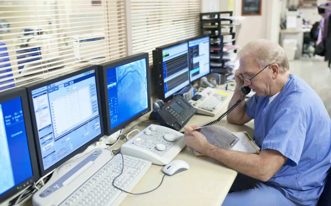 Doctor on phone in front of computers