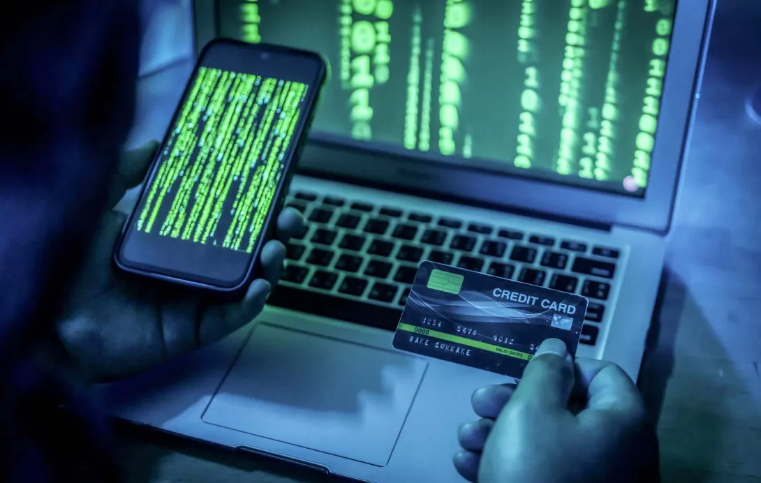 Person on smartphone has credit card out and is also looking at a laptop screen