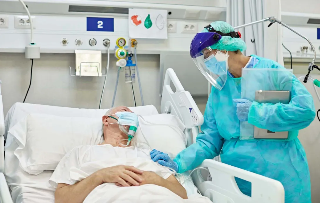 Person wearing PPE at hospital bed