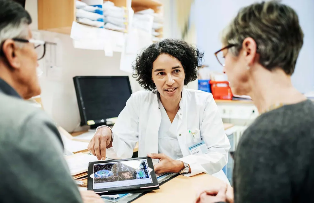 Doctor shows two people tablet screen