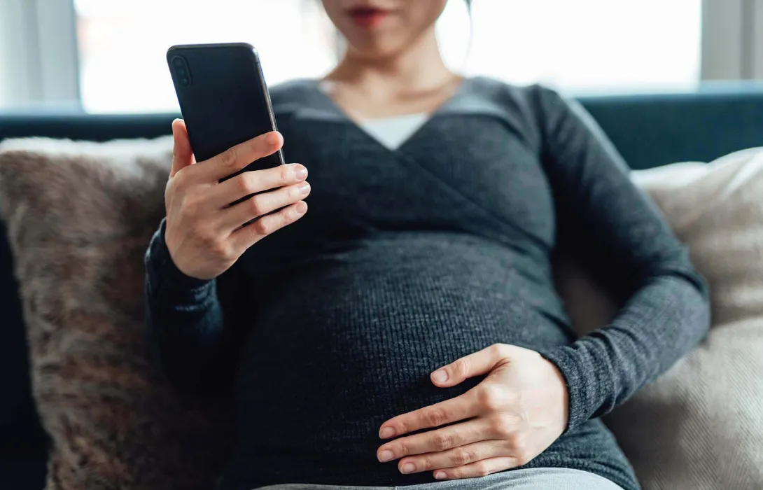 Pregnant person with cellphone. Photo: Oscar Wong/Getty Images