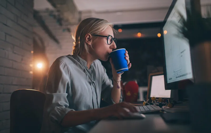 Person at desk sipping from a coffee cup