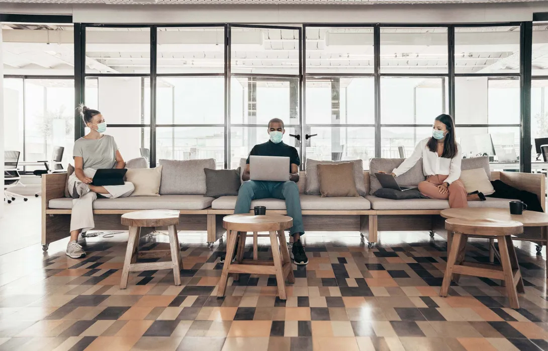 Open office with workers in masks on a couch