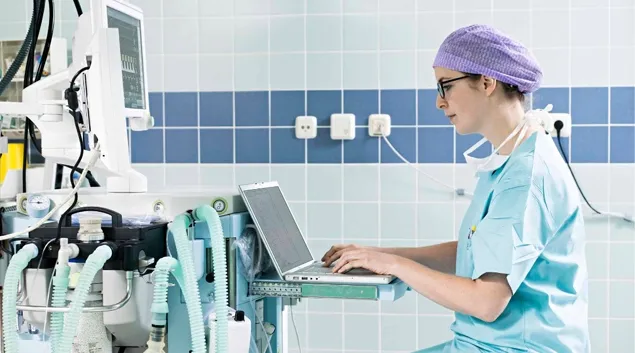 Healthcare professional at laptop in hospital setting