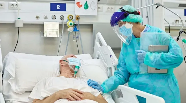 Person in PPE at hospital bedside