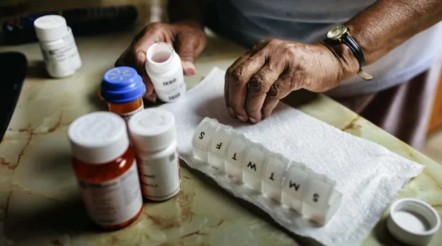 Person with pill bottles and a pill organizer