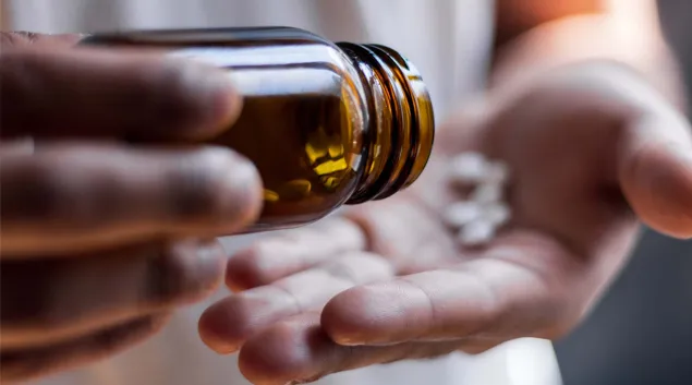 Hands pouring out a bottle of pills
