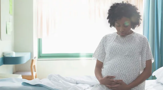 Pregnant person sits on hospital bed