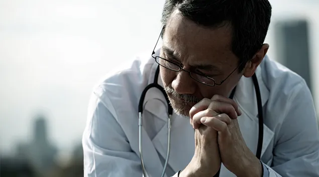 Medical professional seated, appearing dejected