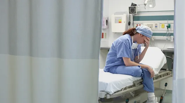 Nurse holding her head in her hand