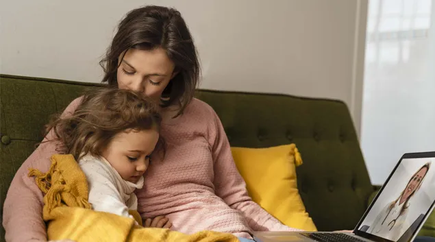 Adult and child in telehealth visit via laptop