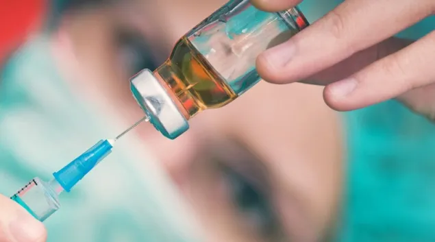 A vaccination dose being drawn from a bottle